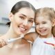 Eine junge Mutter putzt mit ihrem Kind die Zähne